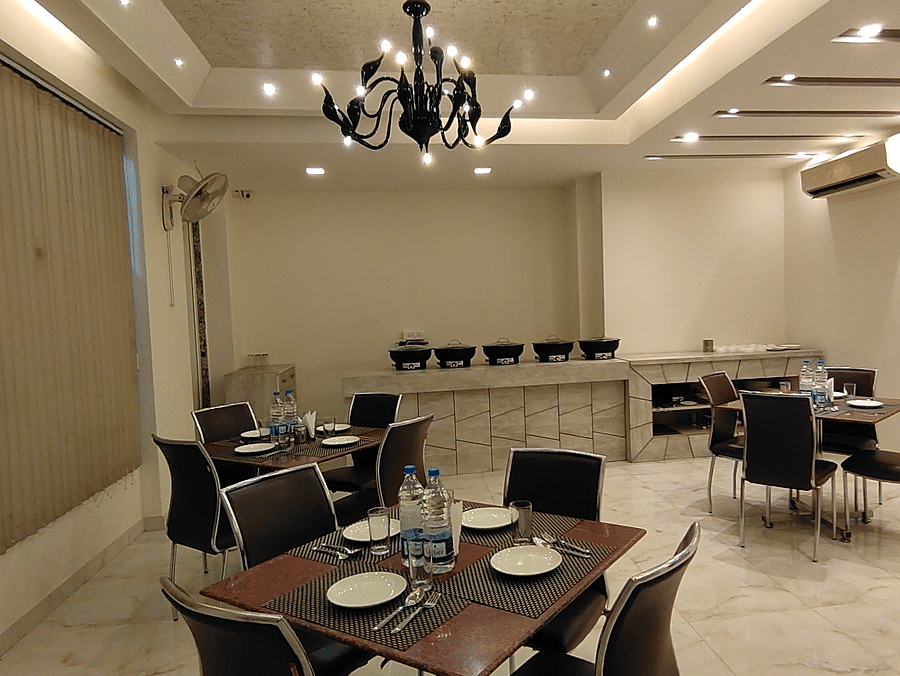 A dining room with set tables and chairs - Asian Suites Cyber Park, Gurgaon.