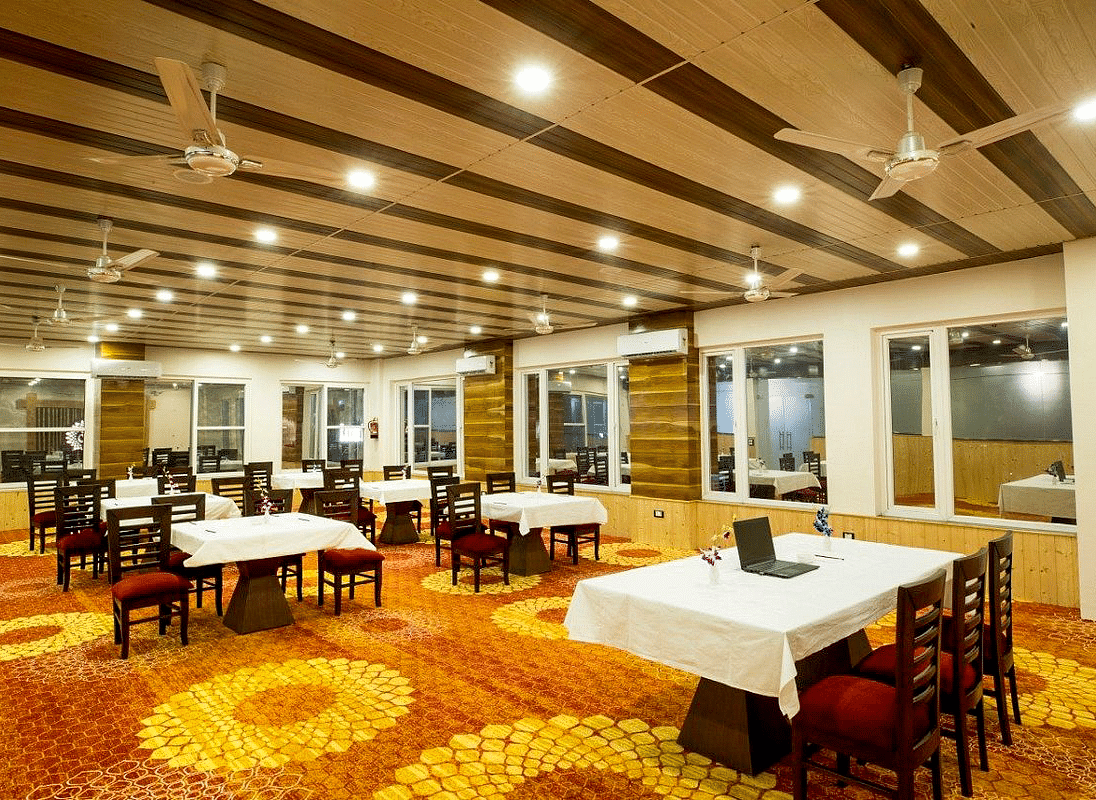 Corner view shot of the banquet hall at Regenta Inn DLS with panel lights and ceiling fans attached on the ceiling.