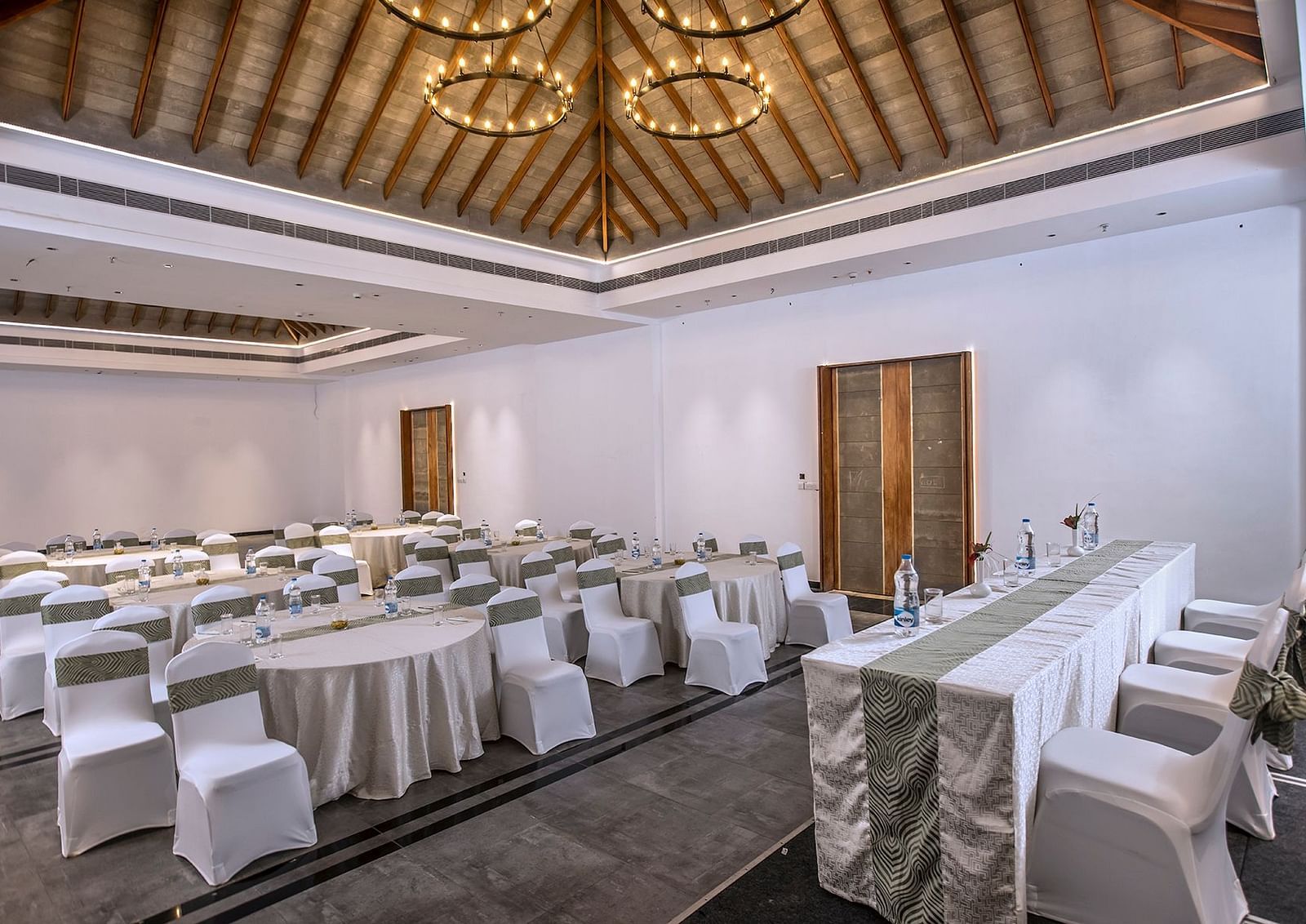 Another angle of the banquet hall with round tables and chairs | Great Trails Wayanad by  GRT hotels.