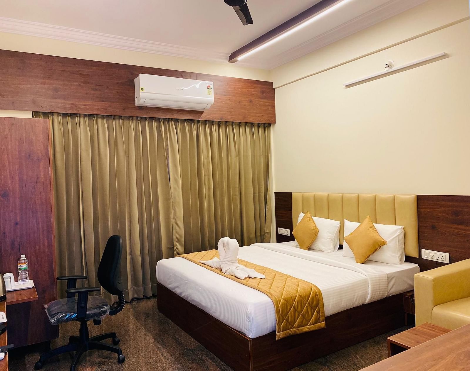 Warm, inviting bedroom with elegant curtain backdrop and work desk at Hotel Sahara Tree.