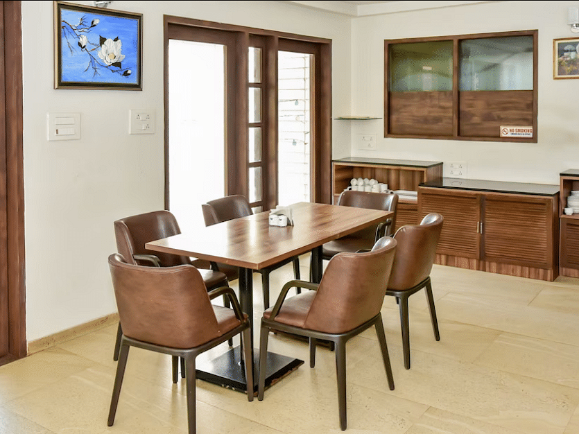 Dining area with a wooden table and chairs, part of the inn's interior at La Vida Studio Inn Goa.