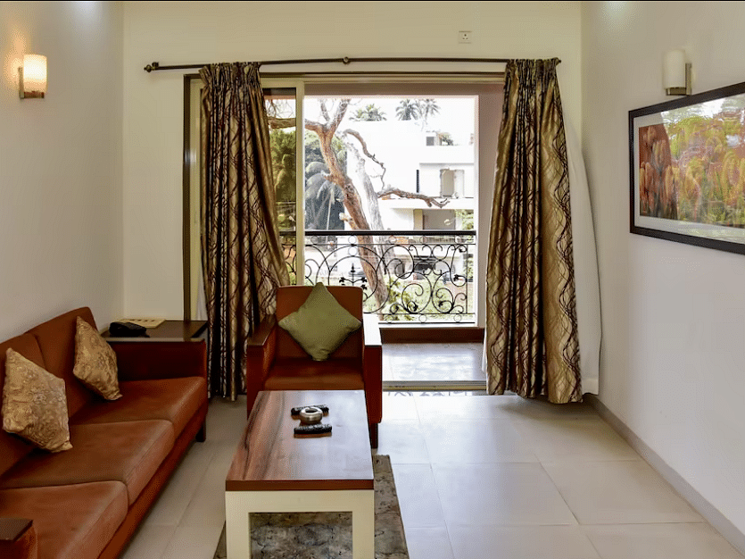 Living area with a sofa, table, and balcony view at La Vida Studio Inn Goa.