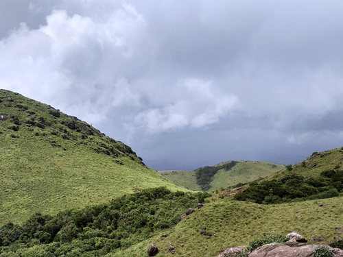 Lush green hills with stormy clouds hovering in the background.