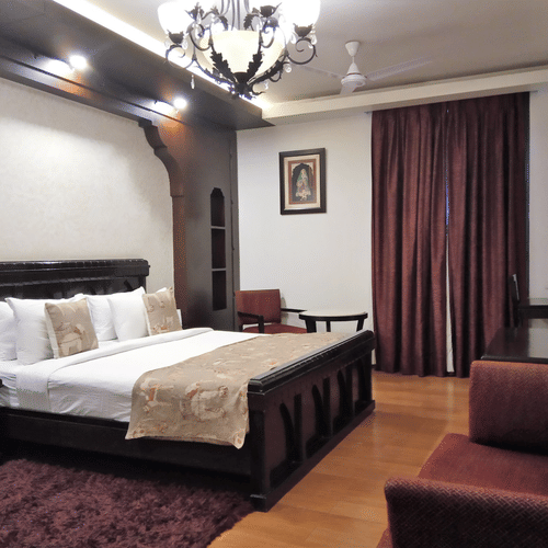 Elegant hotel room at Rockland Hotel, CR Park, featuring classic wooden furniture, chandelier lighting, and warm tones for a luxurious stay.