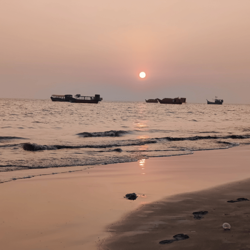 The Balachadi Beach during sunset with a few small boats sailing in the distance.
