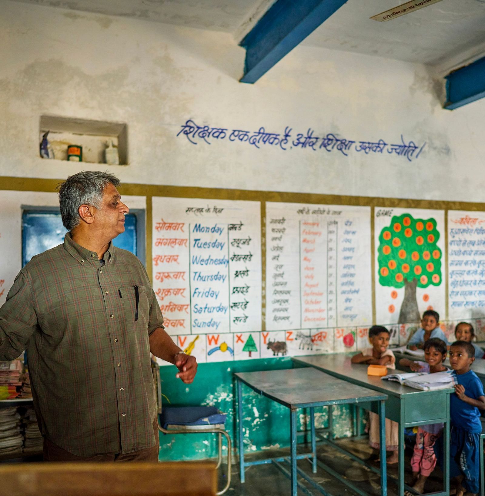 image of an old man teaching with the help of a chalk and blackboard to the students
