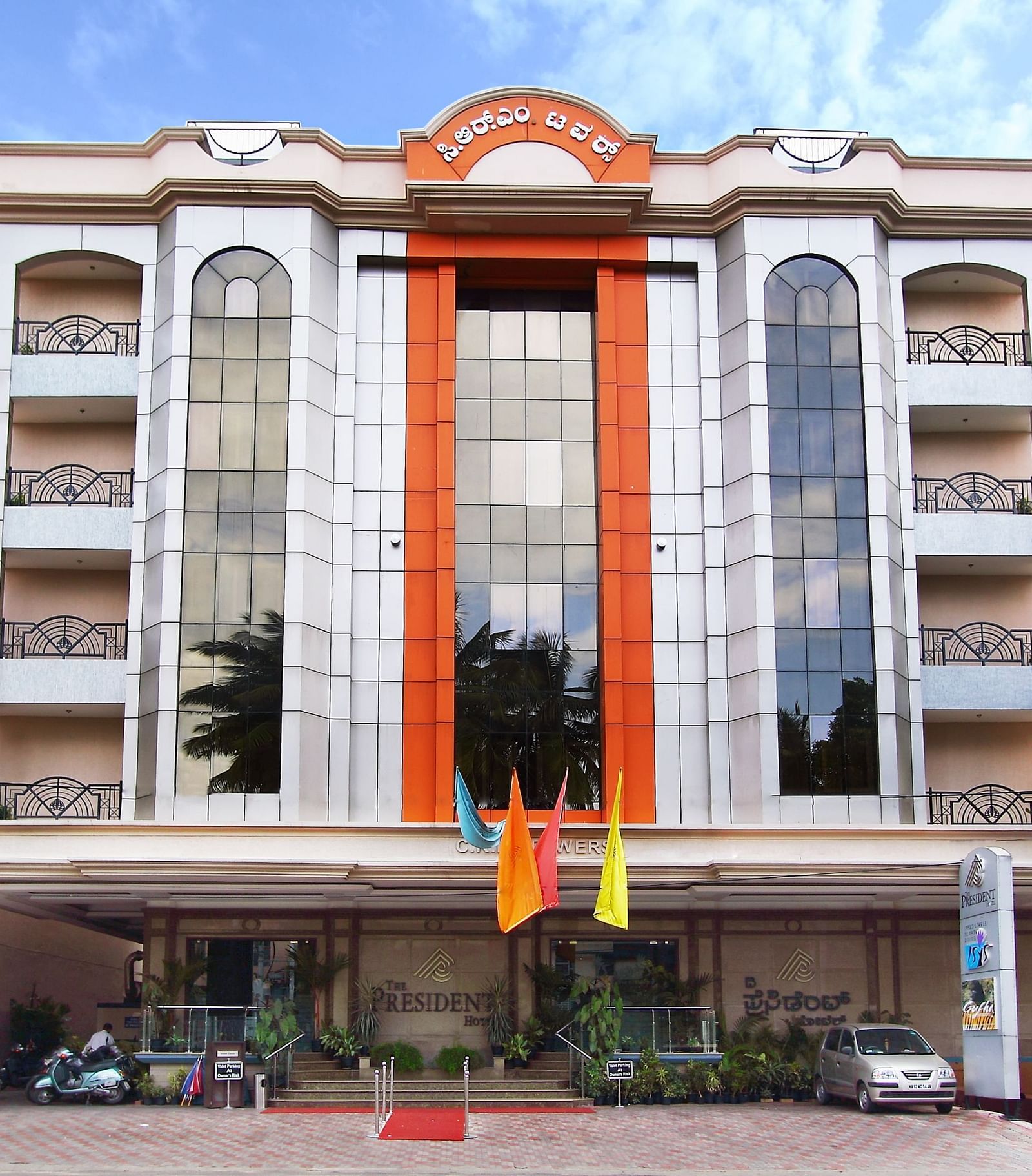 Facade of The President Hotel Jayanagar, Bangalore with striking red accents and a majestic entrance, showcasing a blend of traditional and contemporary architecture 