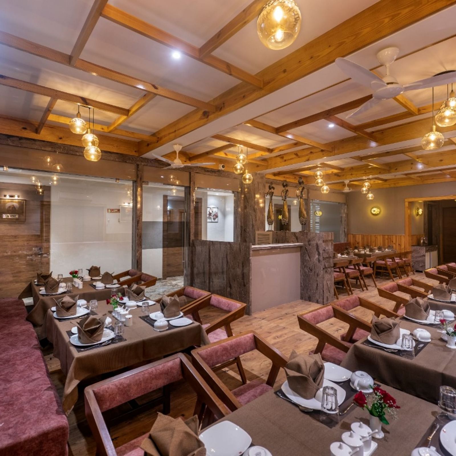 A dining area with multiple tables and chairs set under warm lighting at Angel Lords Eco Inn Amreli.