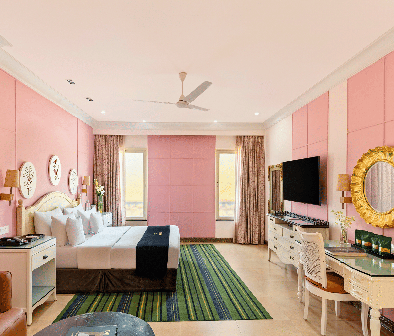 Family room with a king bed, a writing desk, an armchair, a wall-mounted television and curtained windows at MAYFAIR Palm Beach Resort, Gopalpur-on-Sea.