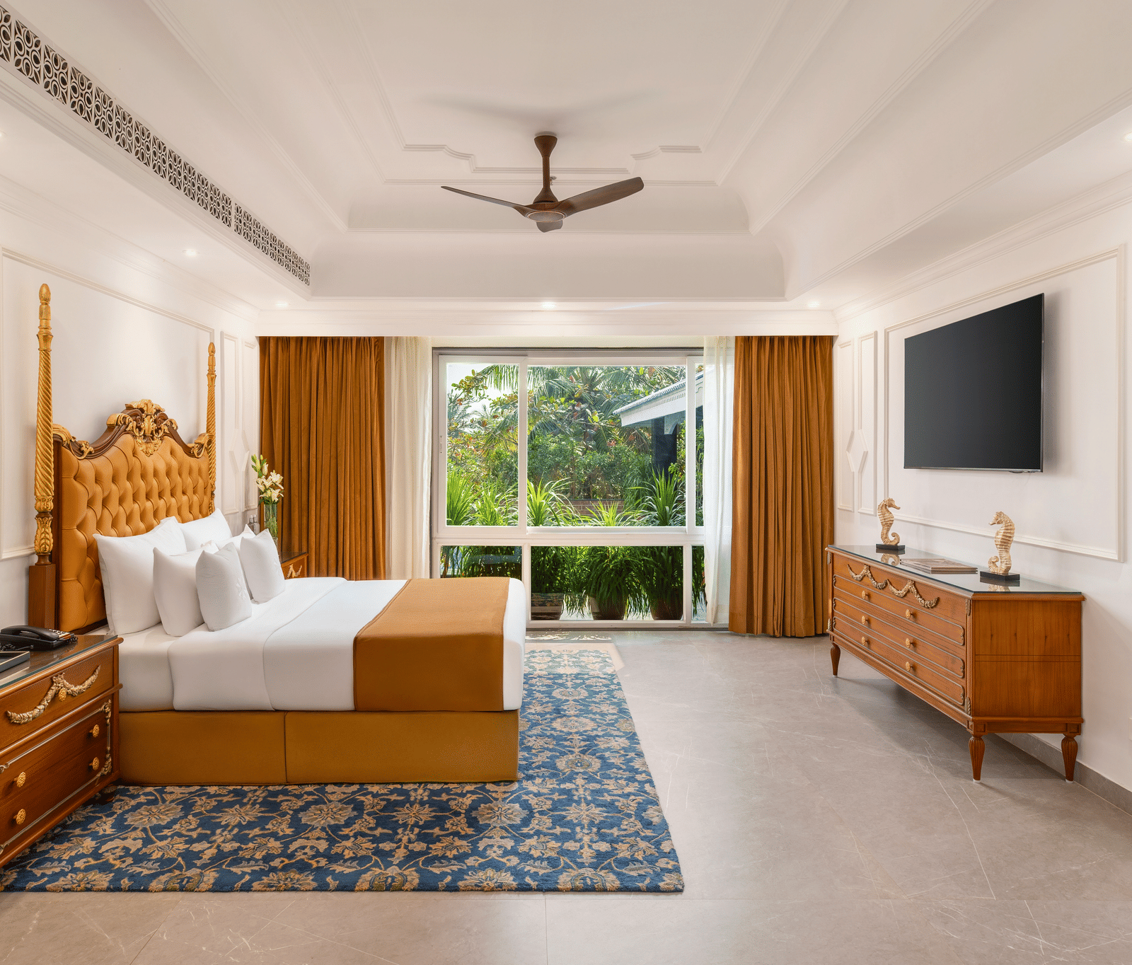 Honeymoon villa with a carved wooden four-poster bed, a dresser, a wall-mounted television and a garden-facing window at MAYFAIR Palm Beach Resort, Gopalpur-on-Sea.