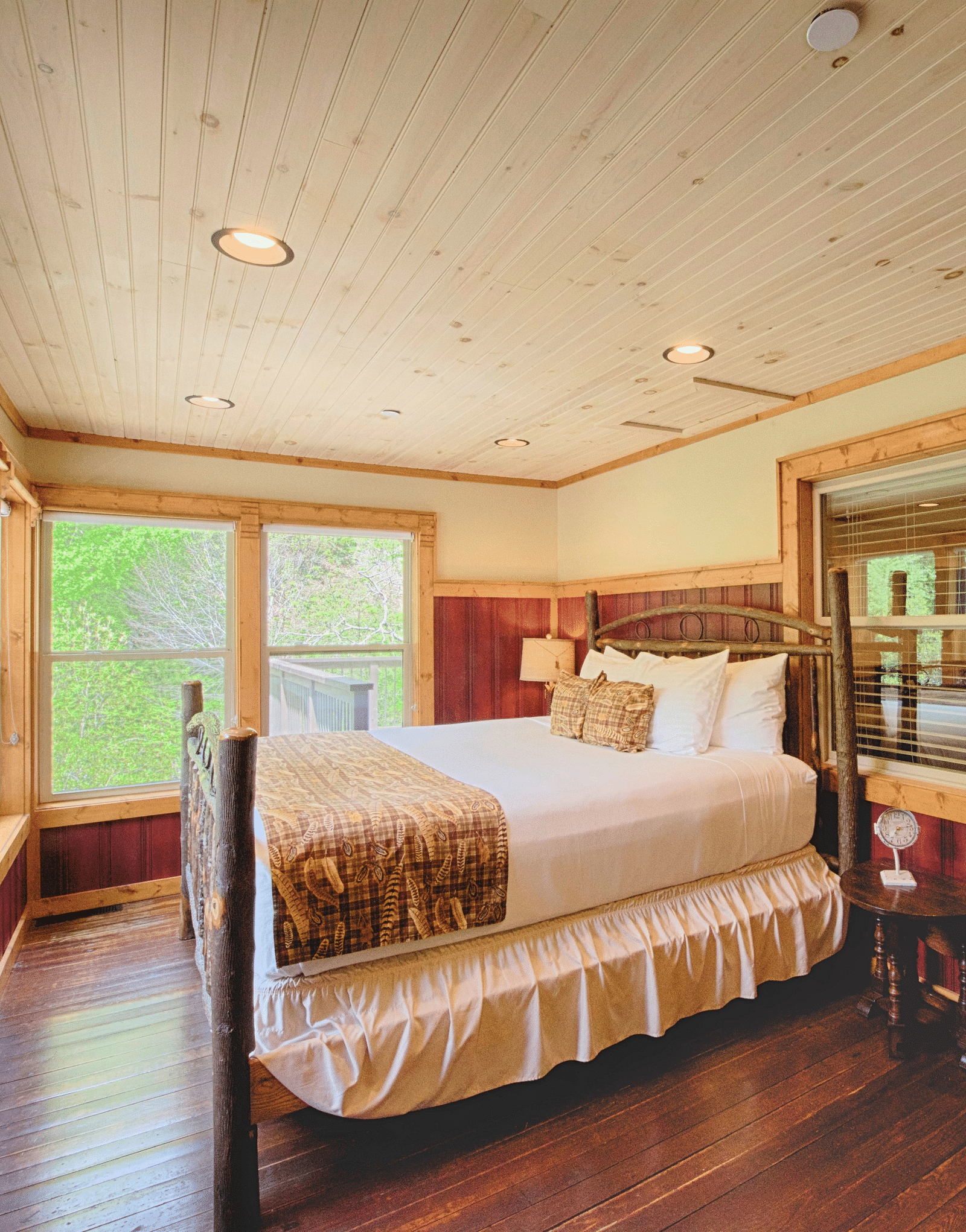 corner view image of a double bed overlooking amazing lush green views from the huge windows in front of it - Historic Tapoco Lodge