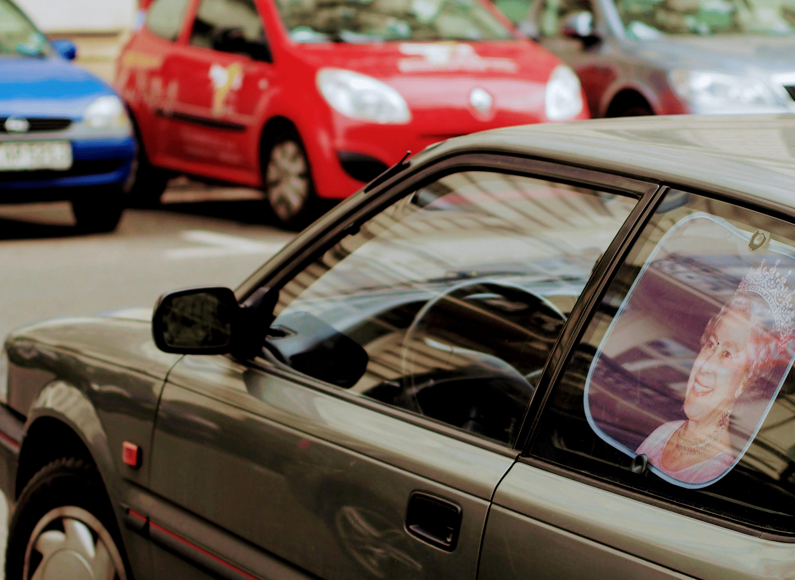 Different coloured cars parked next to each other with a brown car in the foreground.
