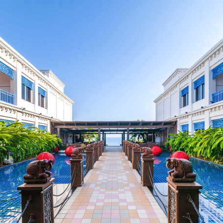 Central courtyard with tiled reflecting pools, carved elephant statues, red lanterns and an archway framing the sea at MAYFAIR Palm Beach Resort, Gopalpur-on-Sea.