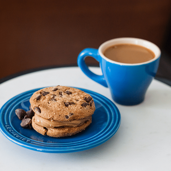 Stack of cookies on a plate with a cup of coffee.