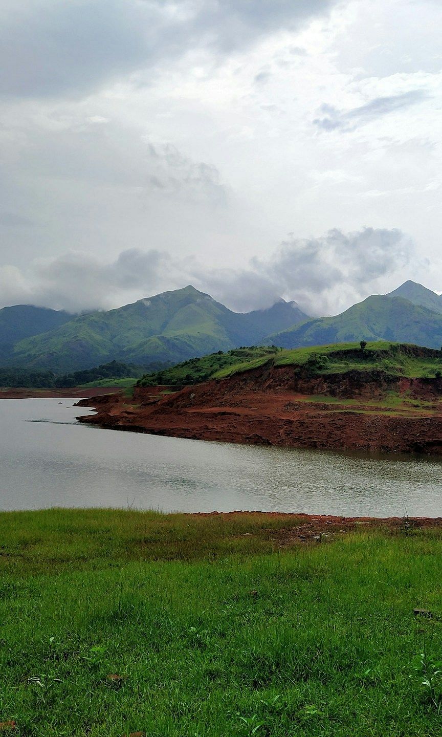 A large  water body surrounded by mountains and a cloudy sky