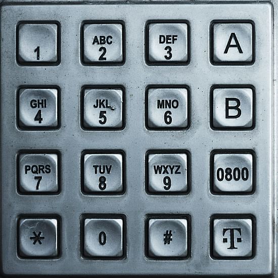 Close-up of a metallic keypad panel with engraved numerals and symbols, possibly for access control.
