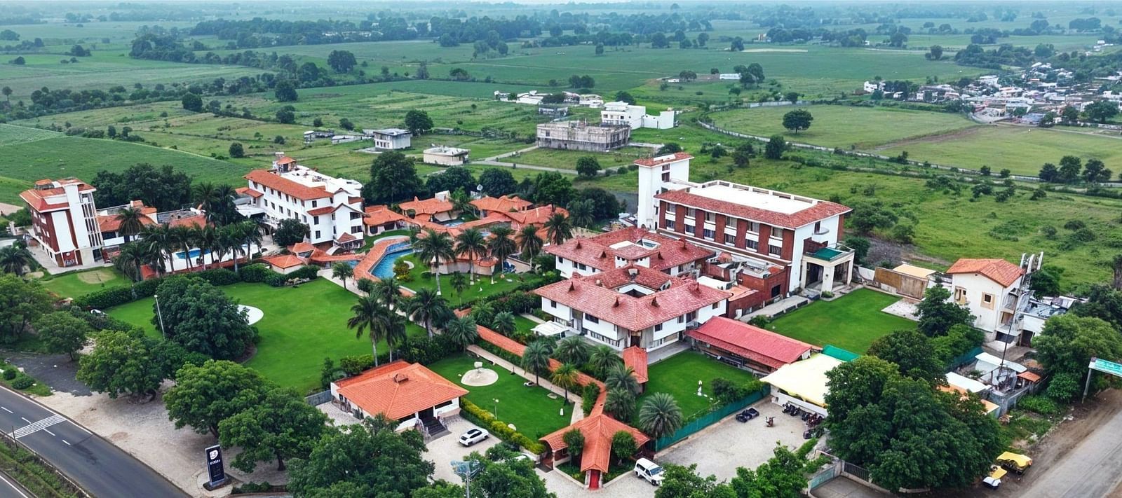 A birds eye view of a large collection of building placed in the middle of some greenery - Crescent Resorts