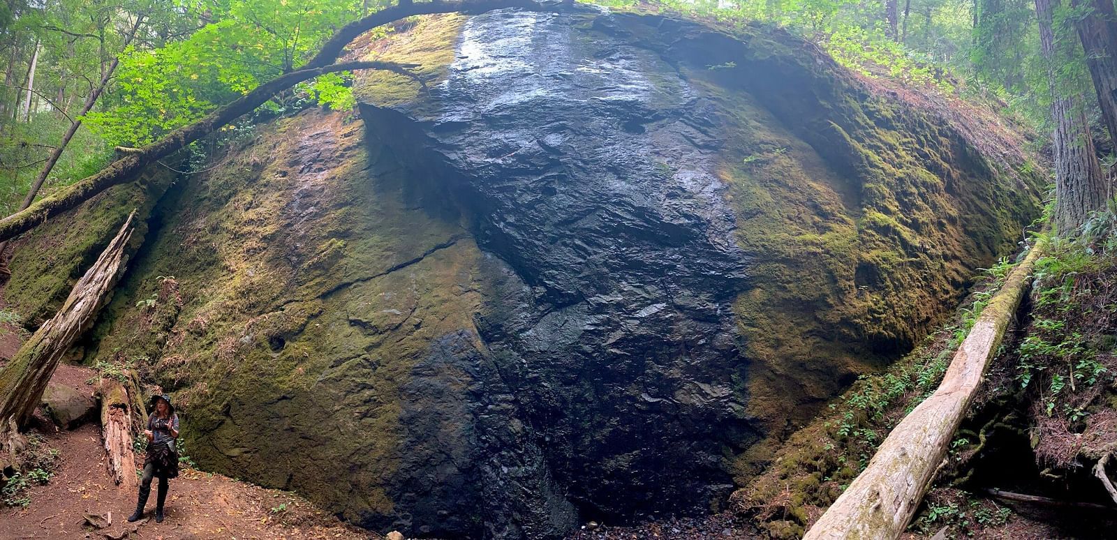Massive rock formation with a small waterfall, showcasing nature’s raw beauty