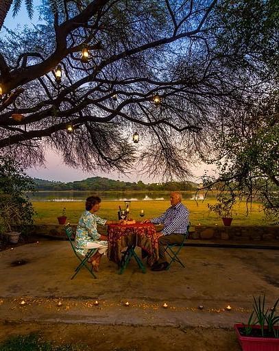 a couple enjoying an open air romantic dinner with a beautiful sunset in the background at Dev Shree, Deogarh