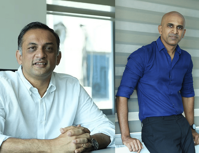 Baahubali producers Sobhu Yarlagadda and Prasad Devineni posing during a professional portrait session in a modern office setting.