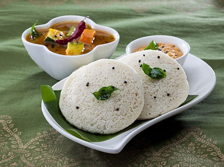 Idly served with sambar and chutney as side dishes.
