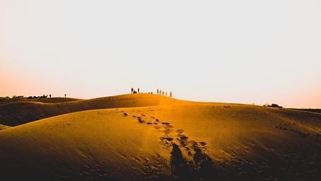 An image of the desert shot during sunset where people are seen walking in the background