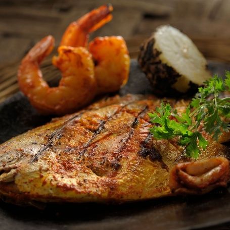 Grilled fish with shrimp, potato, and parsley garnish.
