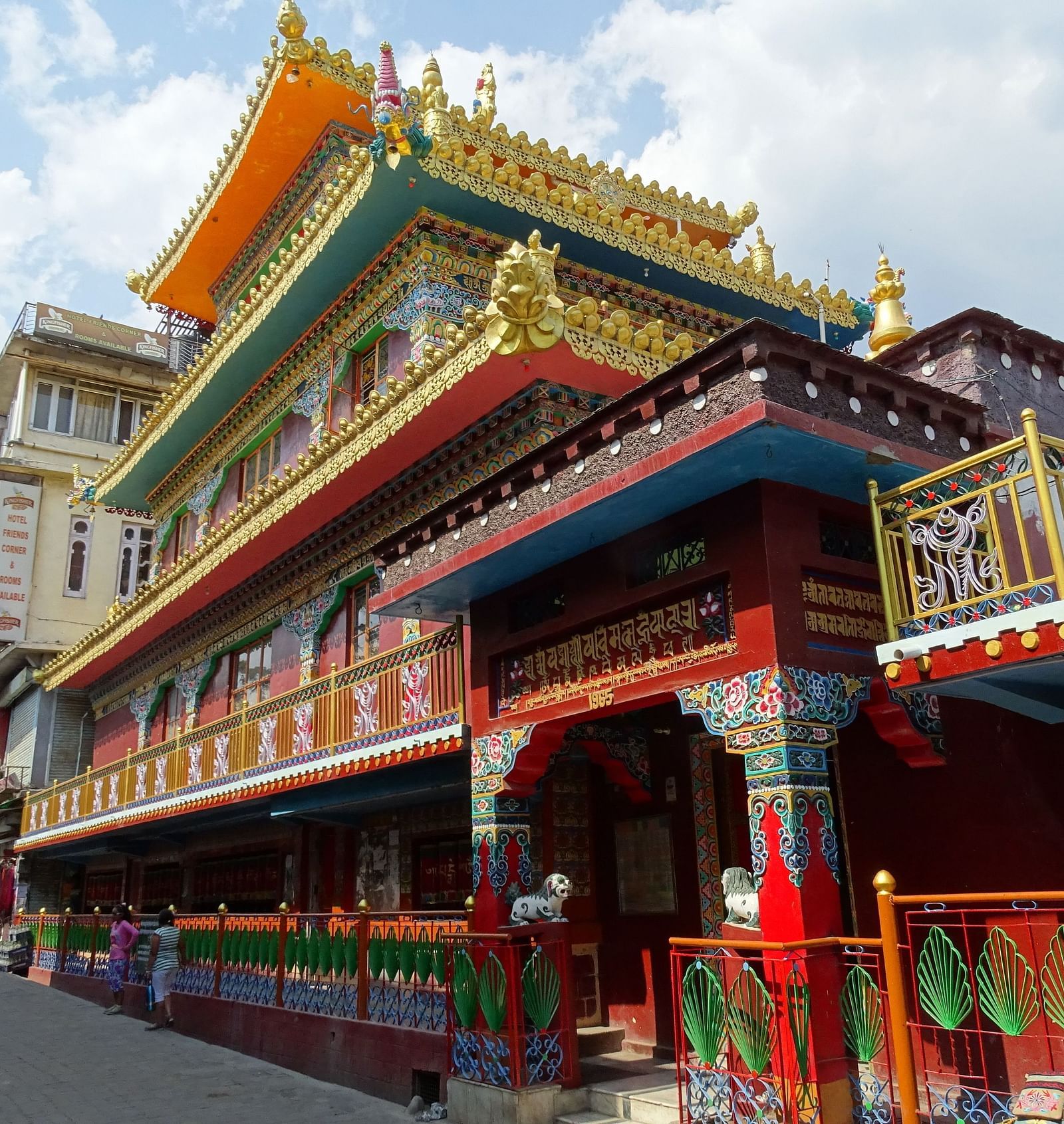 An image of a monastery near a road where people are seen walking