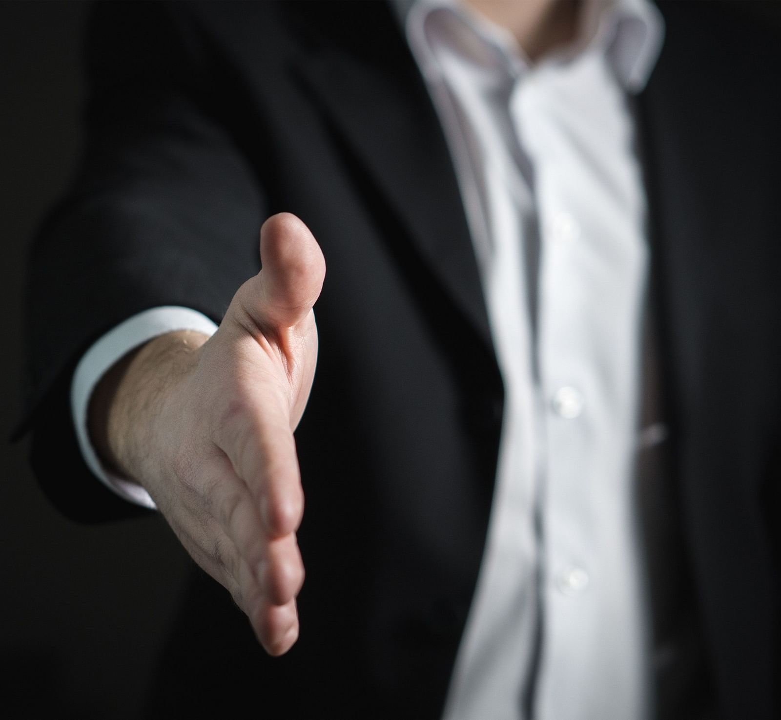 image of a man dressed in business formals extending his hand for a handshake