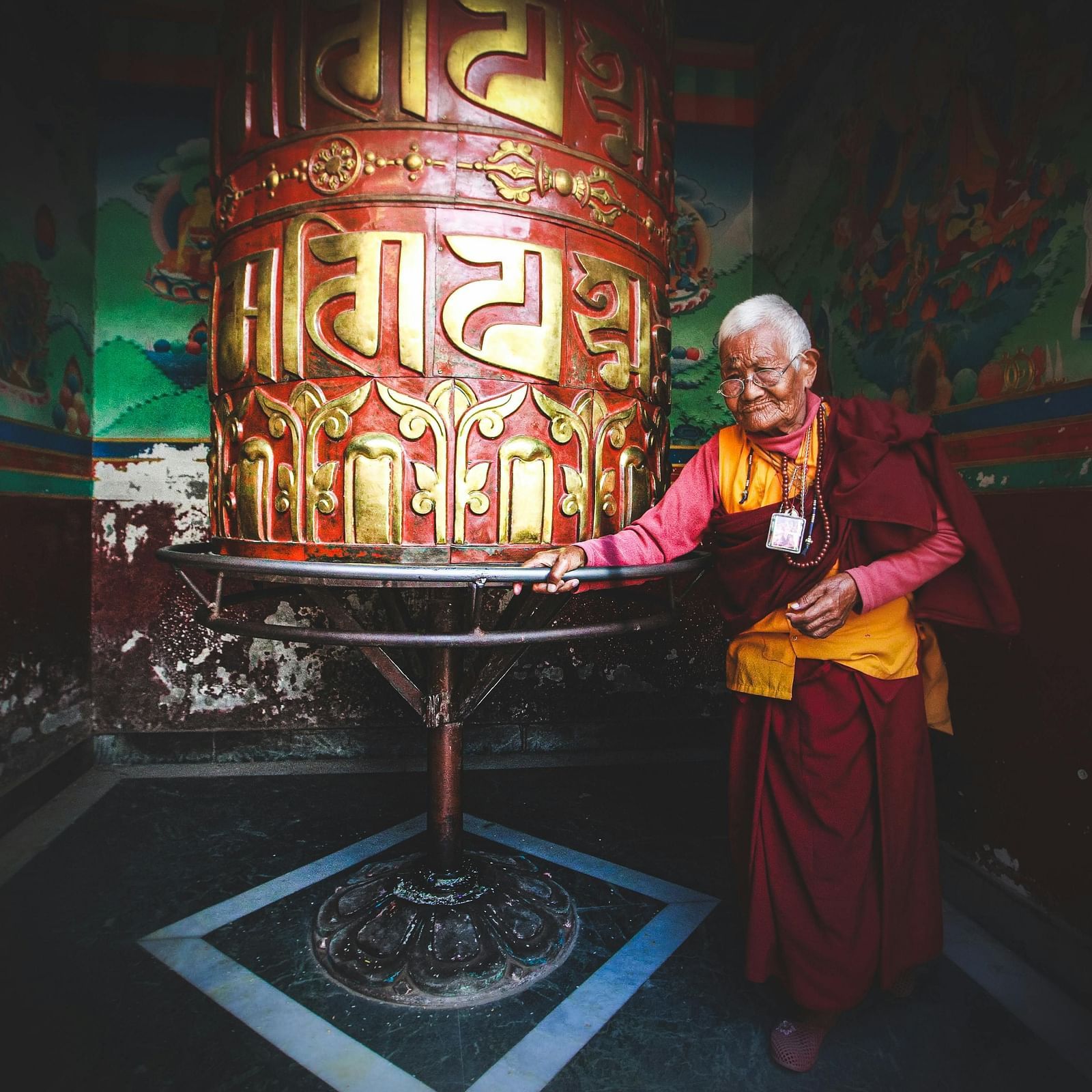 image of an old Buddhist monk circling around a prayer wheel