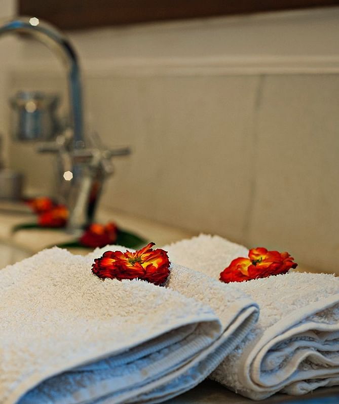 Close-up of towels with flower petals next to a sink in the bathroom - Shreyas Retreat