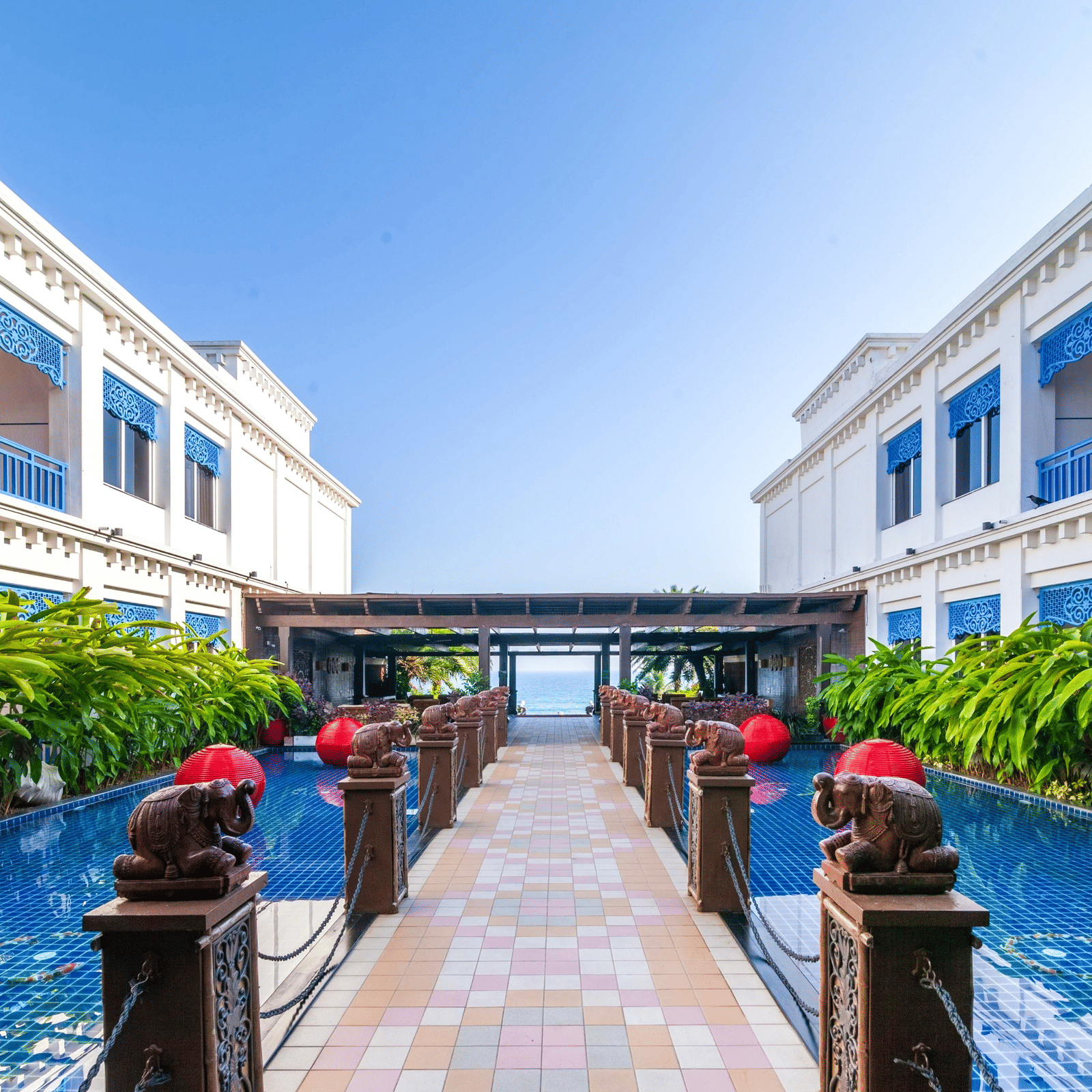 Central courtyard with tiled reflecting pools, carved elephant statues, red lanterns and an archway framing the sea at MAYFAIR Palm Beach Resort, Gopalpur-on-Sea.