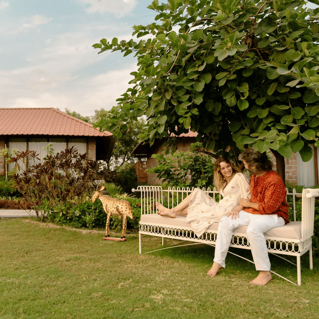 A man and woman sitting on a bench in an outdoor setting at Surpura Bagh.