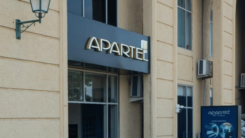 A grand arched entrance to a shop or office in a classical-style building, featuring a traditional green wall lantern and signage at Apartel by Aarin, Oragadam.