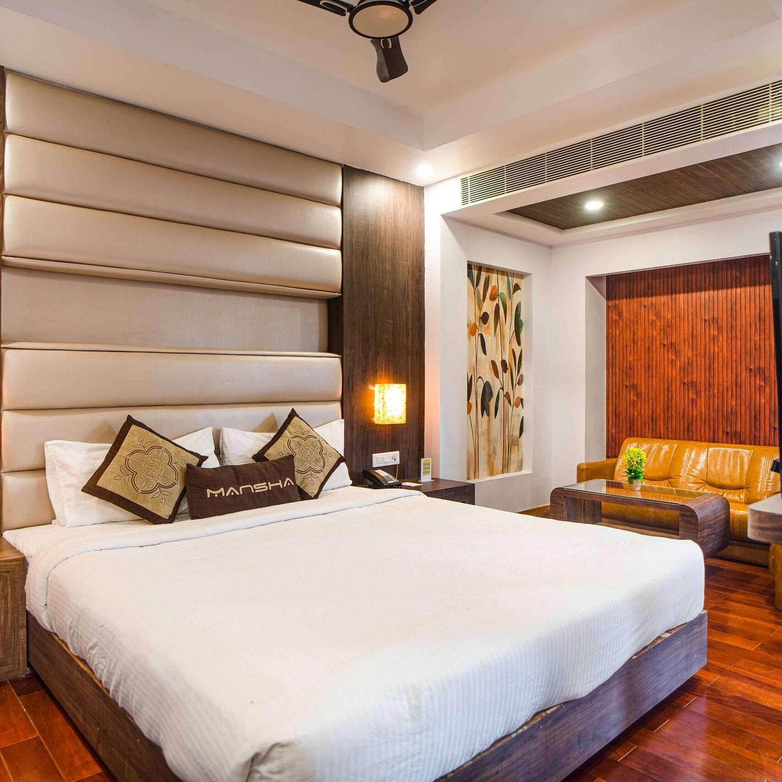 A room at Mansha Hotel Regency featuring a bed with a large headboard, bedside table, and other room amenities.