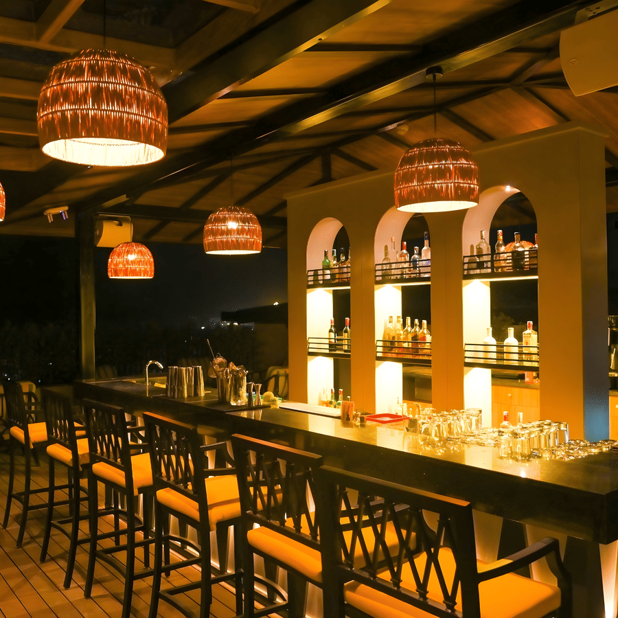 Indoor bar at The Terrace, Aloha on the Ganges, Rishikesh, featuring backlit shelves, high bar stools, and warm pendant lighting.