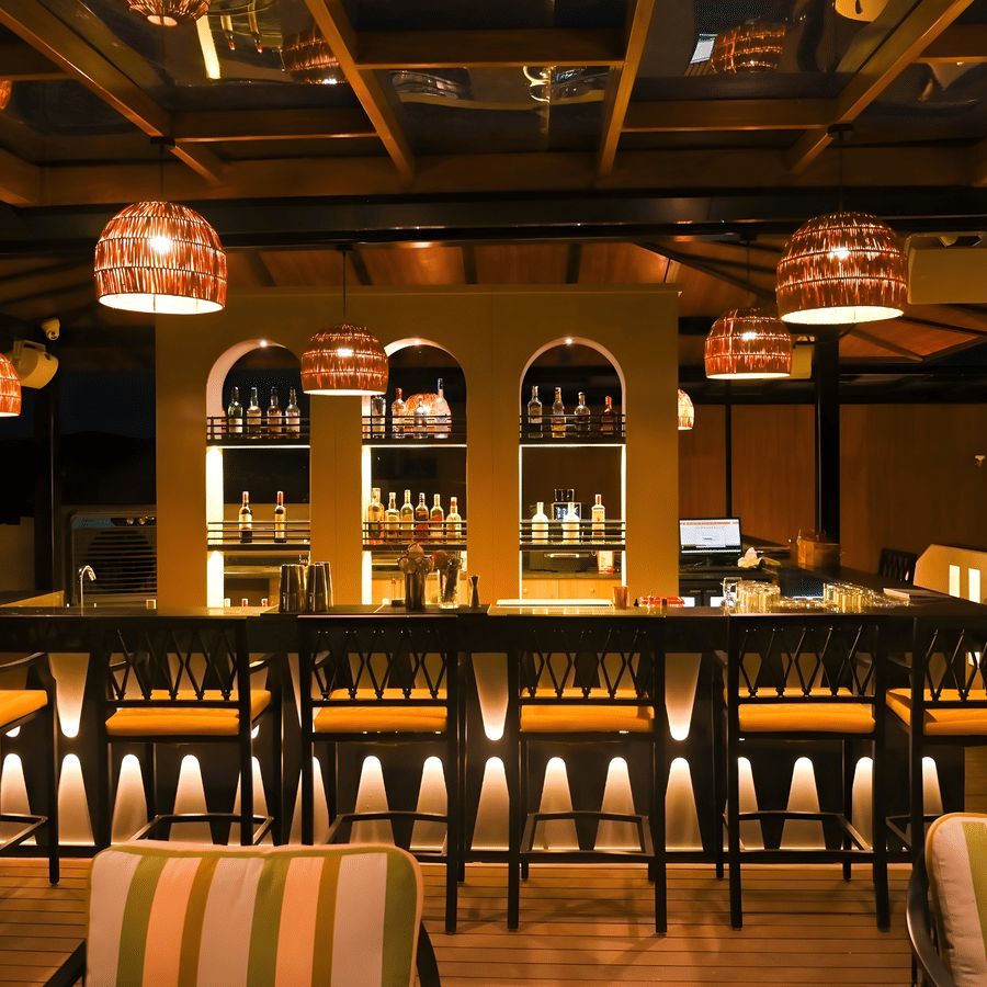 Contemporary bar lounge at The Terrace, Aloha on the Ganges, Rishikesh, with striped seating, wooden interiors, and decorative pendant lights.