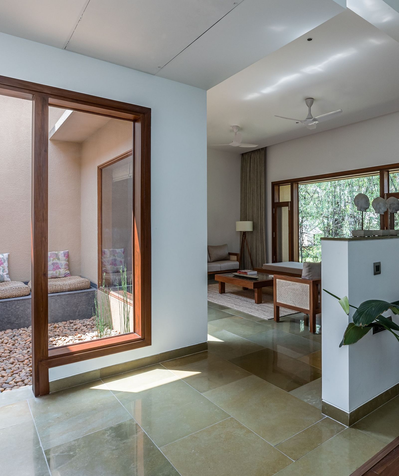 A room with sliding glass doors, a couch, and a view of a garden, bright interior - Shreyas Retreat