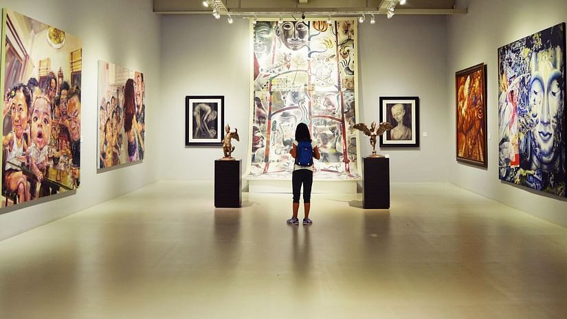 A girl staring at paintings hung on the wall in a museum