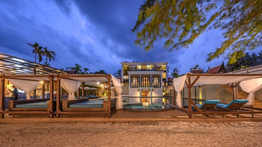 image of cushioned hang out areas in the beach front with a swimming pool in the back on a late evening - Maikhao Dream Villa Resort & Spa, Phuket