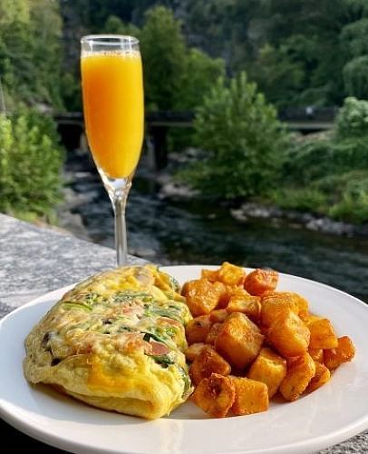 a fluffy omelette served with a glass of fresh orange juice besides the river - Historic Tapoco Lodge