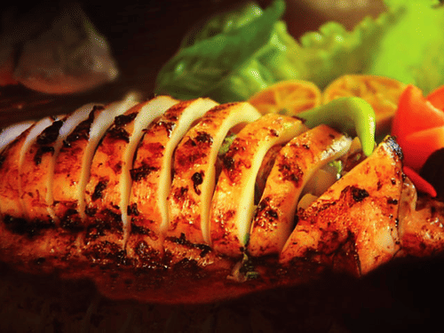 Grilled, sliced calamari served on the platter with vibrant green lettuce and colourful red and yellow bell peppers.