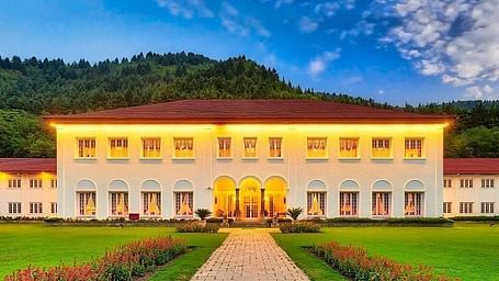 A front view of The Lalit Grand Palace Srinagar with a green lawn in front
