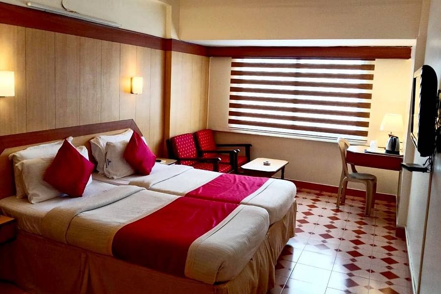 Room with double bed, seating space, a work station, a mini bar, and a wall-mounted TV at Hotel Swagath, Bangalore