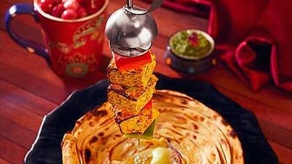 Array of colourful spices and a traditional dish placed on a vibrant table setting.