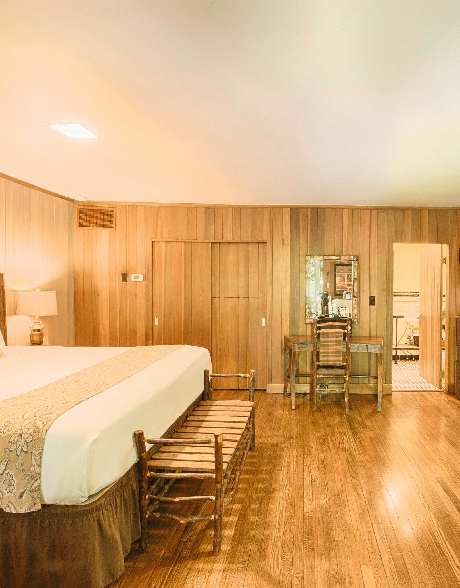corner view image of a brightly lit room featuring a double bed with a wide window right opposite to it - Historic Tapoco Lodge