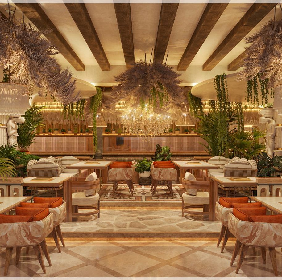An dining hall featuring a huge chandelier light, tables and chairs with plushy cushions, the area is surrounded by plants and statues - Themis Barbecue House
