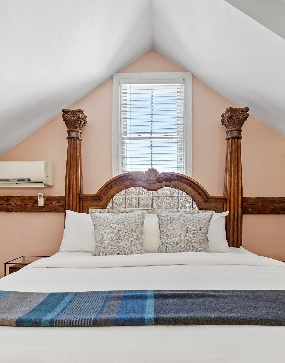 A bedroom with sloped ceiling, skylights, and carved wooden bed at Hartstone Inn.