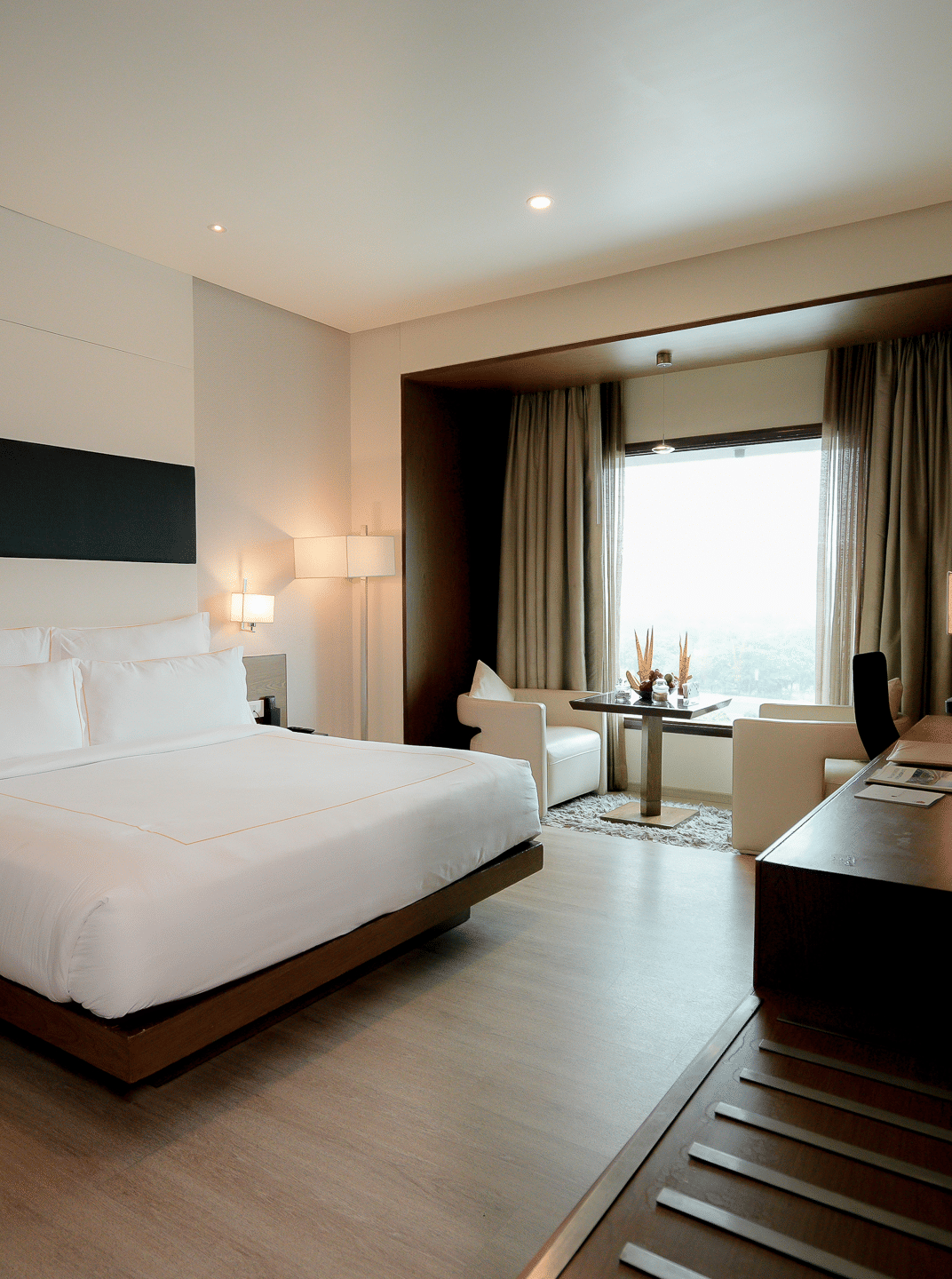 Spacious hotel room with minimalist decor at Narayani Heights Hotel & Resorts, Ahmedabad.