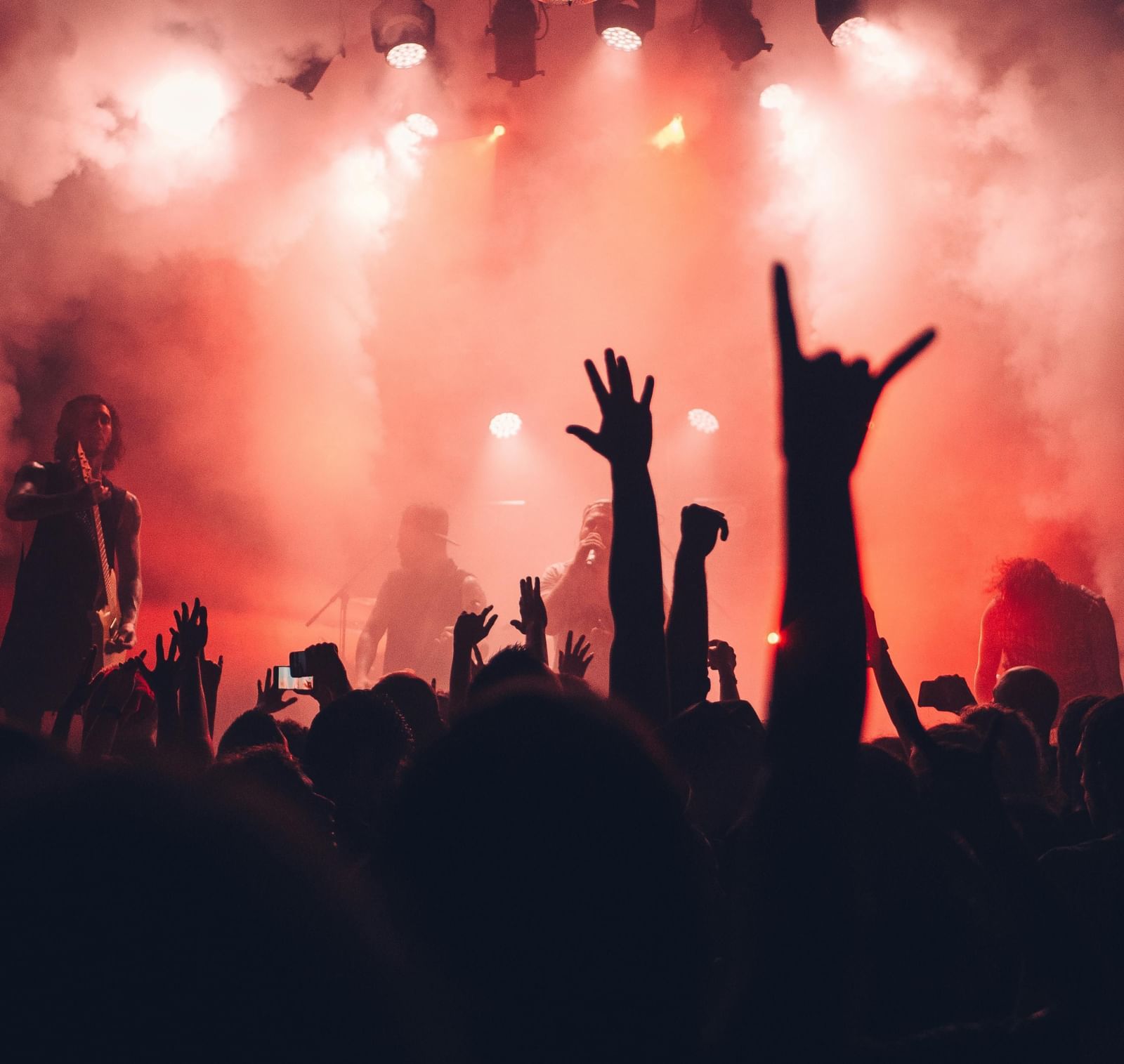 A silhouette of a huge crowd in a party overlooking the stage in front of them.